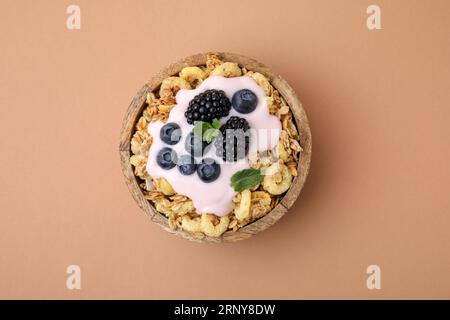 Leckeres Granola, Joghurt und frische Beeren in der Schüssel auf hellbraunem Hintergrund, Blick von oben. Gesundes Frühstück Stockfoto