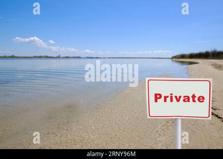 Schild mit Wort Privat am Sandstrand in der Nähe des Flusses Stockfoto