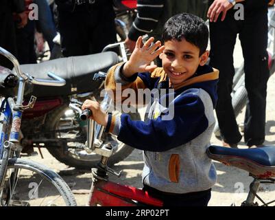 (180414) -- DOUMA, 14. April 2018 -- am 14. April 2018 winkt Ein Junge in Damaskus im östlichen Bezirk Douma, Syrien. Die russische Militärpolizei und die syrischen Polizeikräfte haben gemäß dem am 8. April erzielten Abkommen, nach dem die syrischen offiziellen Institutionen nach Duma zurückkehren werden, mit dem Einsatz in ganz Duma begonnen.) (Zjl) SYRIEN-DAMASKUS-DOUMA-RUSSLAND-EINSATZ AmmarxSafarjalani PUBLICATIONxNOTxINxCHN Stockfoto