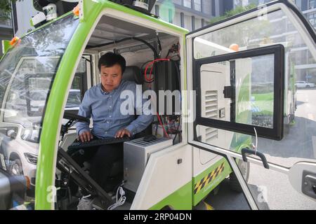 (180418) -- SHANGHAI, 18. April 2018 -- Ein Mitarbeiter debugt eine fahrerlose Straßenkehrmaschine in Shanghai, Ostchina, 18. April 2018. Zwei fahrerlose Straßenkehrmaschinen wurden kürzlich im Shanghai TUs-Caohejing Science Park für Probefahrten eingesetzt. ) (wyl) CHINA-SHANGHAI-DRIVERLESS-STREET KEHRMASCHINE (CN) DingxTing PUBLICATIONxNOTxINxCHN Stockfoto