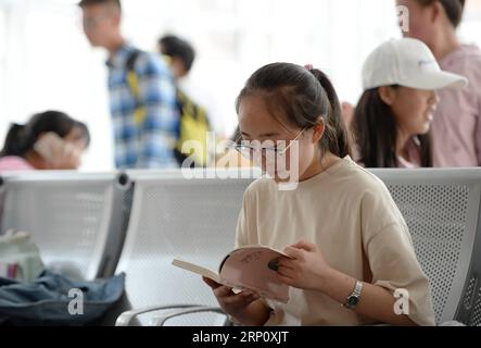 (180529) -- XI AN, 29. Mai 2018 -- Feng Yaoxin liest Buch im Warteraum des Baishuijiang-Bahnhofs in der nordwestchinesischen Provinz Guansu, 27. Mai 2018. Der Zug Nr. 6063, der 38 Stationen entlang der Strecke von Baoji der Provinz Shaanxi und Guangyuan der Provinz Sichuan verbindet, bedient Tausende von Schülern, die in Bergregionen leben und jede Woche von Schulen nach Hause pendeln müssen. Zur Verbesserung der Leistungen für die Schülerpassagiere wurden Ende 2017 Sonderwagen mit größeren Schreibtischen und einer Bibliothek in Betrieb genommen. Mit dem Ansatz der diesjährigen International Stockfoto