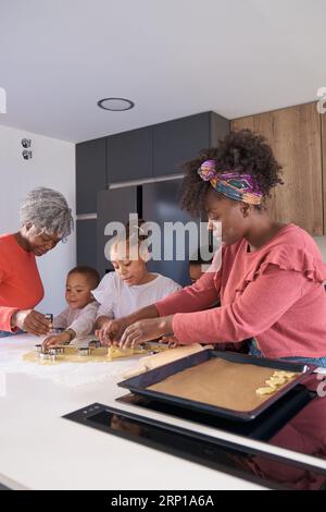 Afrikanische Familie schneidet Keksformen in einem Keksteig in der Küche. Horizontale erweiterte Familie. Stockfoto