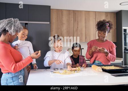 Afrikanische Familie schneidet Keksformen in einem Keksteig in der Küche. Horizontale erweiterte Familie. Stockfoto