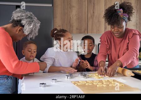 Afrikanische Familie schneidet Keksformen in einem Keksteig in der Küche. Horizontale erweiterte Familie. Stockfoto