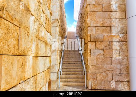 Aufsteigende Stufen zwischen zwei Wänden, die in Richtung des leuchtend blauen Himmels führen. Stockfoto