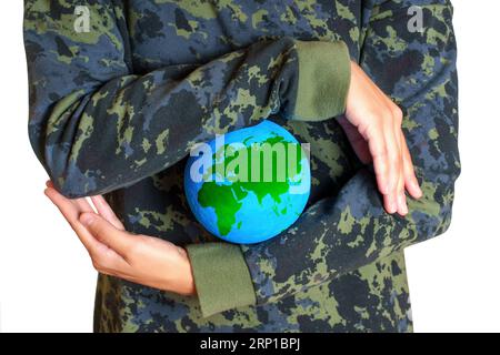 Die Frau, die Tarnkleidung trägt, hält einen kleinen grünen Globus zwischen den Händen isoliert auf weiß. Umweltschutzbezogenes Konzept. Stockfoto