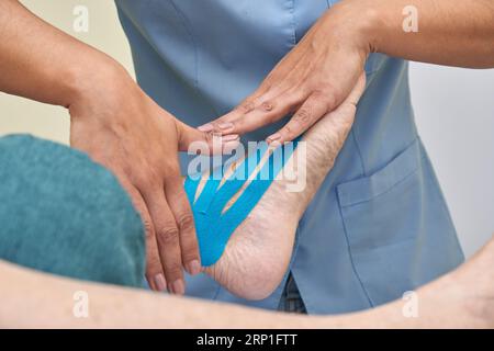 Physiotherapeutin mit blauem kinesio-Band am Bein der Frau Stockfoto