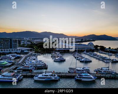 Drohne bei Sonnenuntergang in Cairns Marina und Esplanade mit orangefarbenem Himmel und Bergkulisse Stockfoto