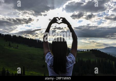 (180715) -- PEKING, 15. Juli 2018 -- Ein Tourist posiert eine Herzensgeste in der Narat Prairie in Narat, Nordwestchinas autonome Region Xinjiang Uygur, 8. Juli 2018. ) (Hxy) XINHUA PHOTO WEEKLY CHOICES (CN) ZhaoxGe PUBLICATIONxNOTxINxCHN Stockfoto