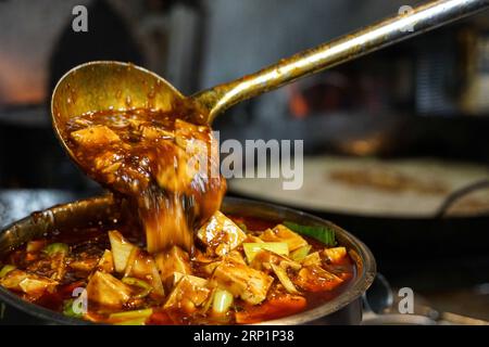 (180717) -- NEW YORK, 17. Juli 2018 -- Ein Koch gießt Mapo Tofu am 27. Juni 2018 in einen Container im Café China in New York, USA. Wenn Sie in der belebten Straße von Midtown Manhattan spazieren gehen, werden Sie das Cafe China vielleicht nicht bemerken, wenn es nicht so viele Leute gibt, die vor dem chinesischen Restaurant auf Sitzplätze warten. Obwohl der Platz begrenzt ist und die Dekoration nicht so luxuriös ist, hat das Cafe China sechs Jahre in Folge von 2012 bis 2017 einen Michelin-Stern gewonnen. Wang Yiming und Zhang Xian, ein Paar aus China, kündigten ihre gut bezahlten finanziellen Jobs in New York und eröffneten Cafe China mit dem Ziel, Autth zu bieten Stockfoto