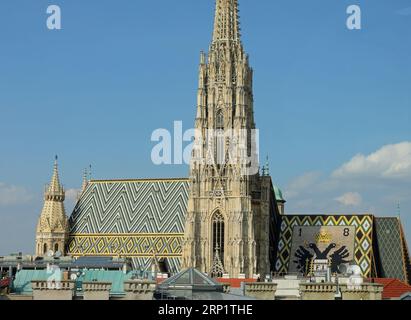 Glockenturm und Dach des Stephansdoms in Wien in Österreich und Doppeladler-Kaiseremblem mit dem Habsburg-Lothringen-Wappen Stockfoto