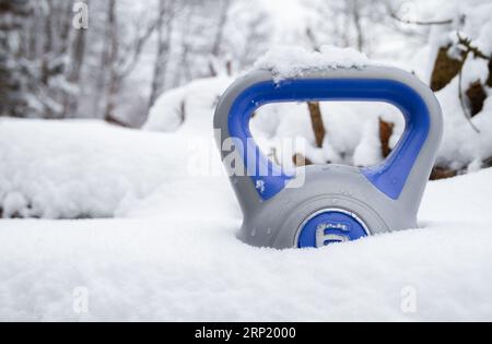 Kettlebell im Tiefschnee. Gesunde Fitness Lifestyle Winterzusammensetzung. Gym-Workout, Sporttrainingskonzept. Training bei kaltem Wetter. Stockfoto