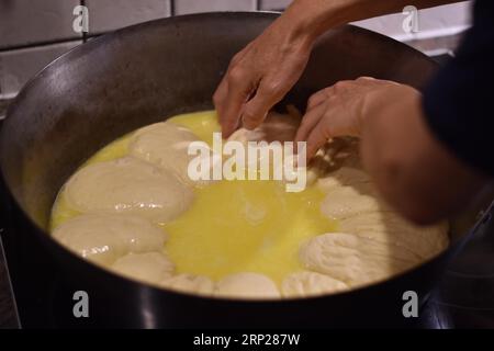 Zubereitung von Dampfnudeln in rustikaler alter Dampfnudelpfanne mit viel Butter, typisch bayerische Küche, Deutschland Stockfoto