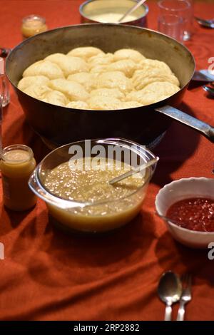 Dampfnudeln in rustikaler alter Dampfnudelpfanne mit Apfelsauce und Johannisbeeren, typisch bayerische Küche, Deutschland Stockfoto