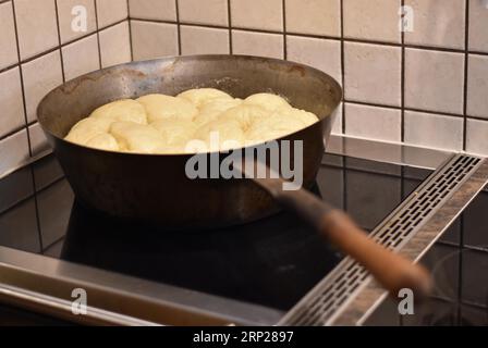 Zubereitung von Dampfnudeln in rustikaler alter Dampfnudelpfanne, typisch bayerische Küche, Deutschland Stockfoto