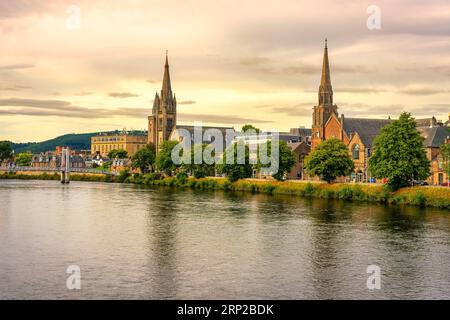 Mittelalterliche Gebäude mit hohen Türmen am Ufer des Flusses Ness bei Sonnenuntergang, Inverness, Schottland. Stockfoto