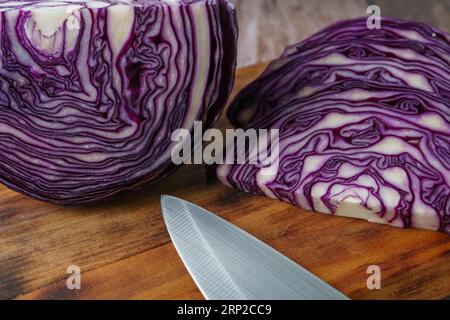 Geschnittener Rotkohl auf einem Holzbrett mit einem Messer im Vordergrund Stockfoto