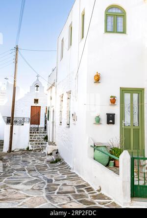 Weiße kykladische Häuser mit grünen Fenstern und Türen, kleine griechisch-orthodoxe Kirche hinten, malerische Gassen des Dorfes Lefkes, Paros Stockfoto