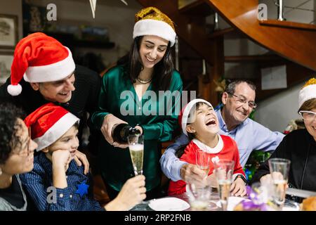 Glückliche Familie mit mehreren Generationen, die Weihnachten feiert und zu Hause zu Abend isst Stockfoto
