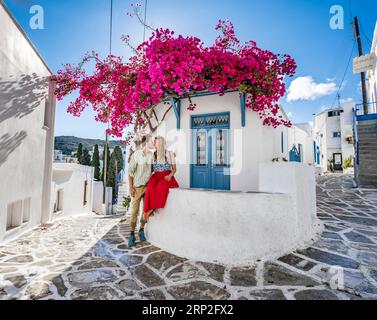 Junge verliebte küssende Paare, weißes Kykladen-Haus mit blauer Tür und rosa Bougainvillea, mit Sonnenstern, malerische Gassen des Dorfes Lefkes Stockfoto