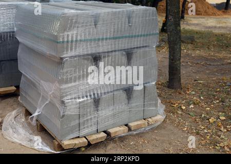 Lager für zementgepresste Materialien auf Holzpaletten Großer Stapel grauer Platten und Aufkantungen für Arbeiten auf der Baustelle in der Straße. Laufsteg reparieren Stockfoto