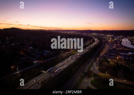 Dieses Bild zeigt eine belebte Autobahn während der abendlichen Hauptverkehrszeit, auf der mehrere Fahrzeuge die Autobahn entlang fahren Stockfoto