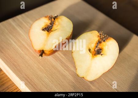 Beschädigte Birnen auf Holztisch. Birnen mit Schnecke auf Schneidebrett. Saftige Früchte. Herbstwirtschaft. Herbsternte. Rohe Lebensmittel. Stücke von süßer Birne. Stockfoto