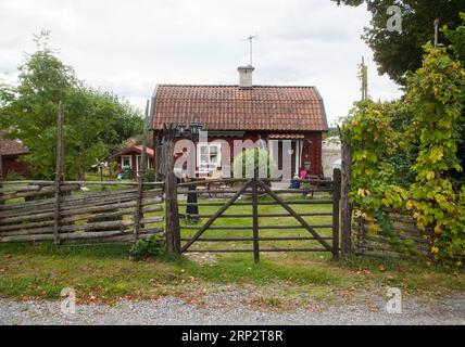 Schwedisches Sommerhaus auf dem Land mit einem Rundpfahlzaun und einem traditionellen Tor Stockfoto