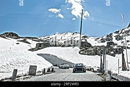 Foto mit reduzierter Dynamiksättigung HDR von zwei Porsche 911, die auf Bergpass Almstraße Almpass Straßenpass alte Gotthardstraße fahren Stockfoto