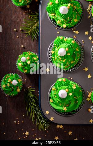 Süße grüne Cupcakes aus grüner Creme zu Weihnachten. Einzigartiges Dessert in den Weihnachtsbaumformen. Stockfoto