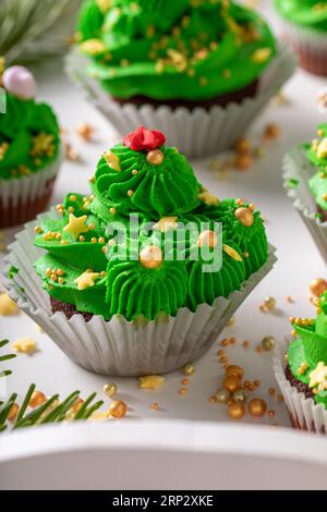 Schöne grüne Cupcakes aus grüner Creme zu Weihnachten. Einzigartiges Dessert in den Weihnachtsbaumformen. Stockfoto