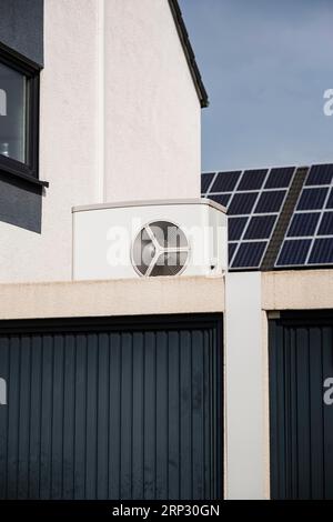 Wärmepumpe auf einem Garagendach eines Neubaus, im Hintergrund sind Solarpaneele auf Hausdächern, Monheim am Rhein, Nordrhein-Westfalen montiert Stockfoto