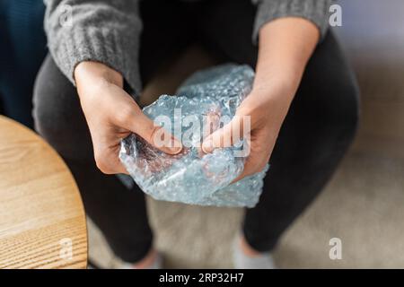 Nahaufnahme von einer Frau, die zu Hause Luftpolsterfolie platzt Stockfoto