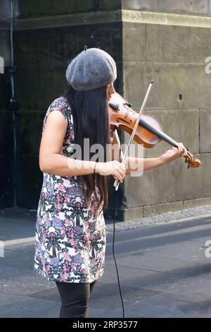 Edinburgh, Schottland, Großbritannien - 15. August 2023: Eine junge Asiatin spielt neben St. Giles Cathedral an Edinburghs Royal Mile während der Fringe Stockfoto