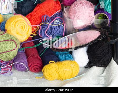 Bunte Wollbälle und ein kleiner Spiegel auf einem Handwerksständer. Horizontal aufgenommen. Stockfoto