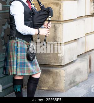 Seitenansicht eines traditionellen schottischen Musikers, der während des Fringe Festivals in Edinburgh, Schottland, die Dudelsack in einem typischen Schottenkotte spielt Stockfoto