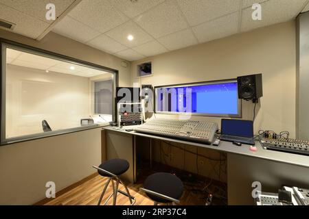 Mischkonsolen in einem kleinen Aufnahmestudio mit mehreren Fenstern Stockfoto