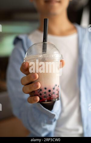 Der Mann hält eiskalten Milchblasentee mit Tapiokaperlen und zeigt ihn vor der Kamera, traditionelles Getränk Taiwans Stockfoto