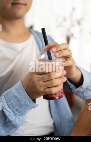 Close-up des Mannes, der kalten Blasentee im Café trinkt Stockfoto