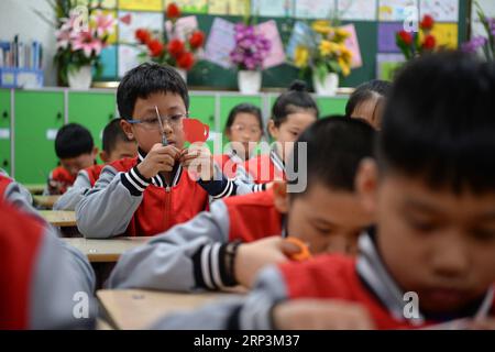 (181010) -- HARBIN, 10. Oktober 2018 -- Schüler üben Papierschneiden an einer Grundschule in Harbin, Provinz Heilongjiang im Nordosten Chinas, 10. Oktober 2018. Seit 2017 hat die Regierung von Harbin ein Service-Programm ins Leben gerufen, bei dem Schüler von mehr als 240 Grundschulen in der Schule bleiben und traditionelle Kulturen lernen können, die von Schulen angeboten werden, während sie darauf warten, dass ihre Eltern sie abholen. ) (Gxn) CHINA-HEILONGJIANG-HARBIN-AFTER-SCHOOL SERVICE (CN) WangxKai PUBLICATIONxNOTxINxCHN Stockfoto