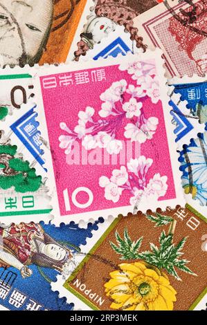 Madrid, Spanien; 13.08.2023: Briefmarke aus Japan mit Kirschblüten auf rosafarbenem Hintergrund mit weiteren Briefmarken, die einen Hintergrund bilden Stockfoto