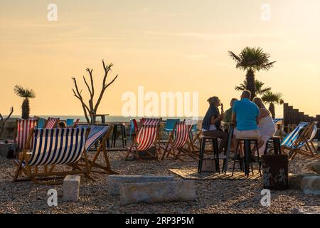 Blick auf die Briten, die am 22. September 2021 in Folkestone, Großbritannien, in einem Strandcafé bei Sonnenuntergang mit Liegestühlen entspannen Stockfoto