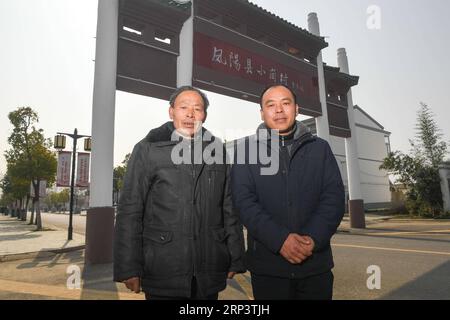 (181016) -- FENGYANG, 16. Oktober 2018 (Xinhua) -- Yan Hongchang (L), ein führender Dorfbewohner, der 1978 die geheime Vereinbarung unterzeichnete, kommunales Ackerland in Familiengrundstücke aufzuteilen, und sein Sohn Yan Yushan posierten am 23. März 2018 vor dem Stadttor Xiaogang im Fengyang County in der ostchinesischen Provinz Anhui für Fotos. Xiaogang liegt im County Fengyang (phoenix). Wie der mythologische Namensgeber hat auch das County im Laufe der Jahrhunderte hunderte von Reinkarnationen durchlaufen, während Gemeinden wie Xiaogang in einer wankelmütigen Umgebung kämpfen, um genug Nahrung zu sich zu nehmen, um zu überleben. 1978 kamen 18 Bauern zusammen Stockfoto