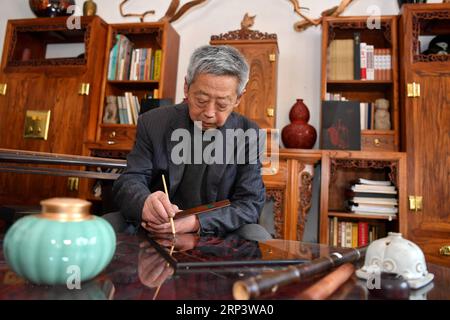 (181017) -- PINGYAO, 17. Oktober 2018 (Xinhua) -- der Handwerker Geng Baoguo legt am 16. Oktober 2018 in seiner Werkstatt in Pingyao, nordchinesische Provinz Shanxi, Farben auf ein Lack. Lacquerwares sind Objekte, die dekorativ mit Lack bedeckt sind. Die lackierten Lacke in Pingyao bestehen aus natürlichem Lack und werden mit einer speziellen Handtechnik lackiert. Nach mehreren Handwerksschritten werden sie mit verschiedenen bunten Mustern verziert und mit Ornamenten versehen. Die Oberfläche der fertigen Lacke ist glatt und glänzend. Mit einer Geschichte von über 1.000 Jahren, war das Pingyao Lackgeschirr Stockfoto