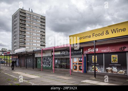 Lokales Einkaufsviertel mit heruntergekommenem Turmblock im Hintergrund. Druids Heath Housing Estate in Birmingham, Großbritannien, 2023. Stockfoto