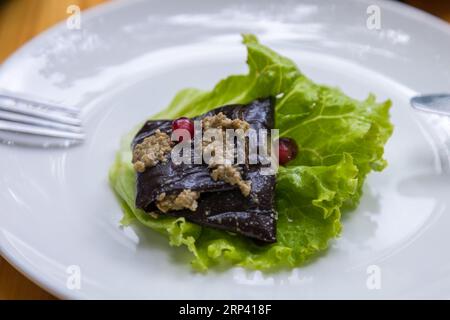 Auberginen-Roulade gefüllt mit Walnüssen und Granatapfelfrüchten mit Knoblauch und georgianischen Gewürzen, serviert auf Salat. Stockfoto