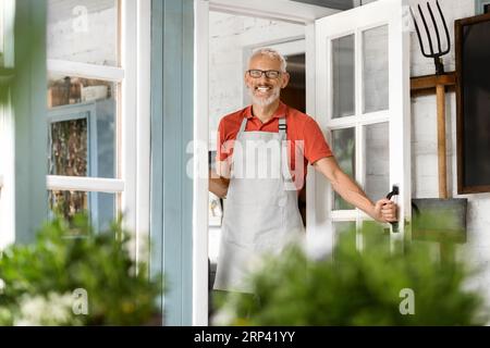 Gutaussehender Reifer Mann, Der Die Tür Öffnet Und Im Country House Willkommen Heißt Stockfoto