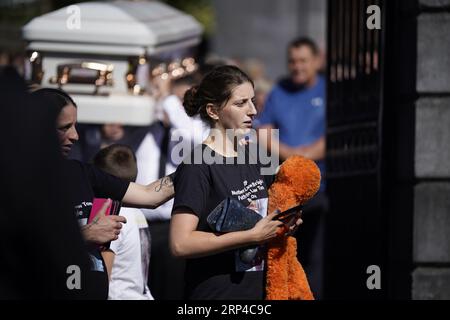 Diane Reilly (trägt oranges Spielzeug) betrachtet den Sarg ihres dreijährigen Sohnes Tom als die Särge von Thomas Reilly, 45, seiner Frau Bridget Reilly, 46, und Tom verlassen die St. John the Baptist Church in Cashel, Co. Tipperary nach ihrem Beerdigungsgottesdienst. Thomas, Bridget und Tom starben am 29. August in Cashel bei einem Unfall mit einem einzigen Fahrzeug. Bilddatum: Sonntag, 3. September 2023. Stockfoto