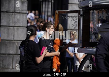 Diane Reilly (trägt oranges Spielzeug) betrachtet den Sarg ihres dreijährigen Sohnes Tom als die Särge von Thomas Reilly, 45, seiner Frau Bridget Reilly, 46, und Tom verlassen die St. John the Baptist Church in Cashel, Co. Tipperary nach ihrem Beerdigungsgottesdienst. Thomas, Bridget und Tom starben am 29. August in Cashel bei einem Unfall mit einem einzigen Fahrzeug. Bilddatum: Sonntag, 3. September 2023. Stockfoto