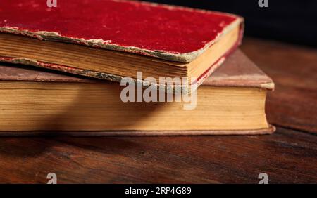 Vintage-Buch auf Holzschreibtisch. Altes Buch aus rotem und braunem Leder auf dunklem Tischhintergrund. Fantasie, Weisheit, Intelligenz, Wissen. Stockfoto